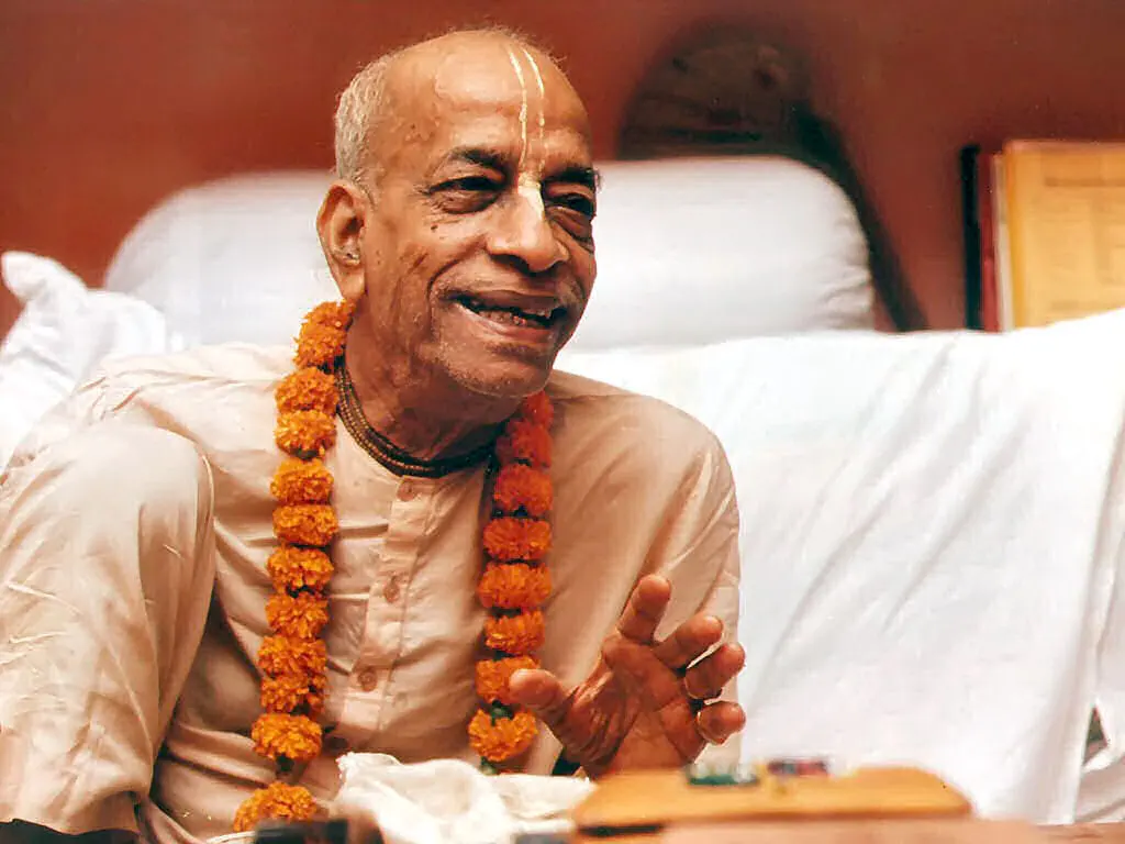 Srila Prabhupada speaking, garlanded with marigolds